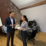 Zak and Sara discussing cloud licensing differences in a UK office environment.