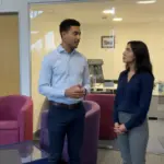 Zak and Sara discussing predictive AI inside a UK office, captured mid-discussion.