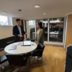 Adam and Sara discussing CRM workflows in a UK office environment.